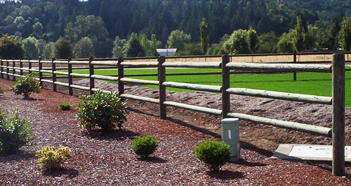 Wooden rail fence with shrubs on a farm