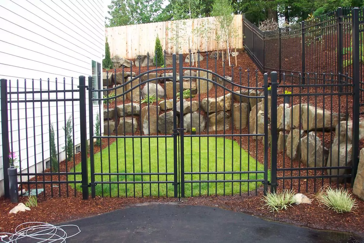 Wrought iron fence with a gate leading to the backyard of a home to illustrate types of residential fences.