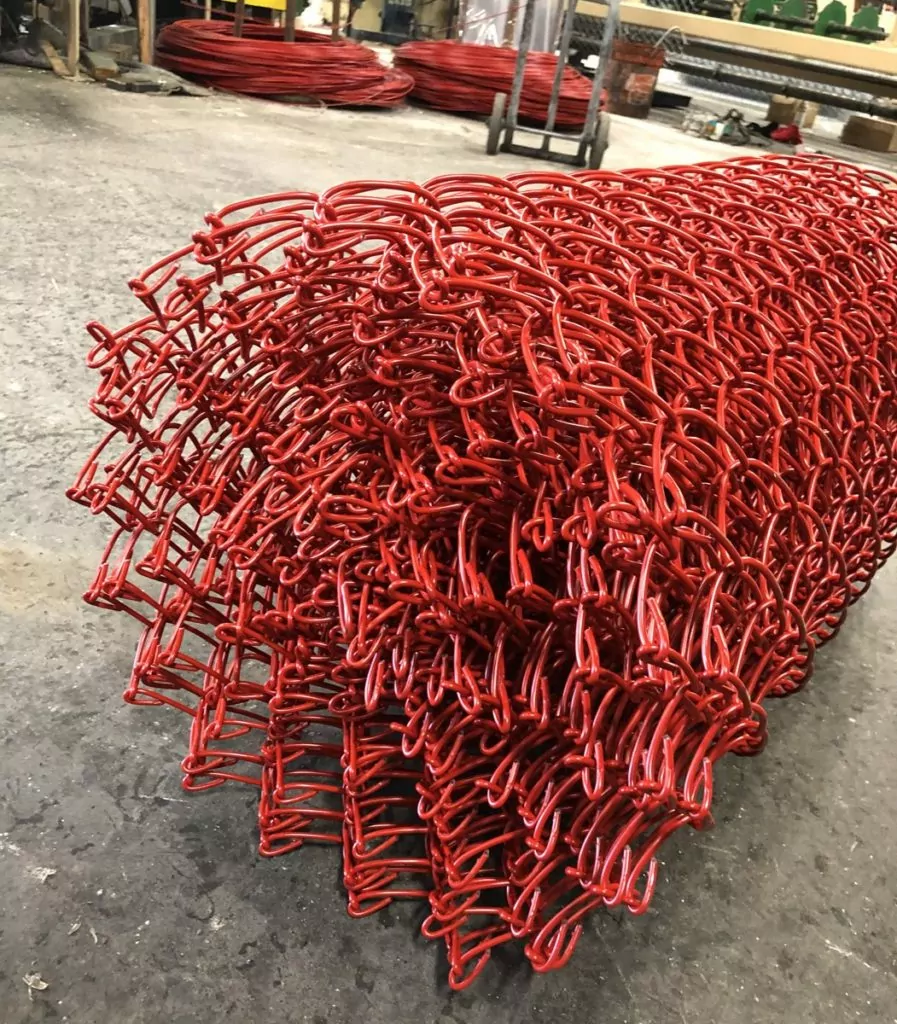 A roll of Chain link fence that has a red vinyl coating.