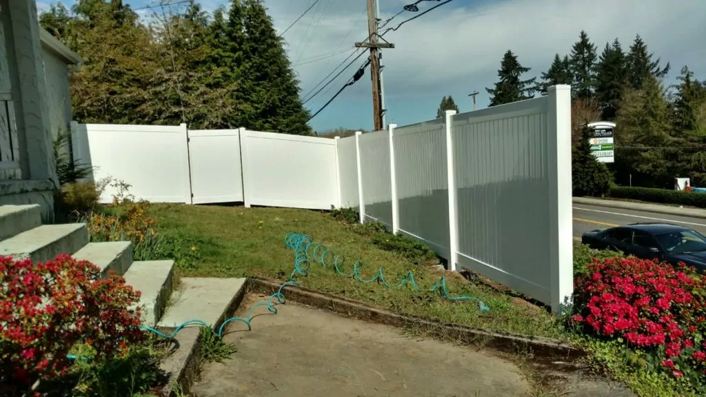 A white vinyl fence in a front yard to illustrate benefits of vinyl fencing