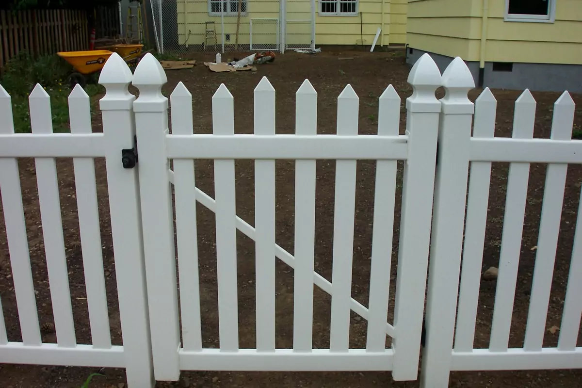 White vinyl picket fence with a gate to illustrate types of residential fences.