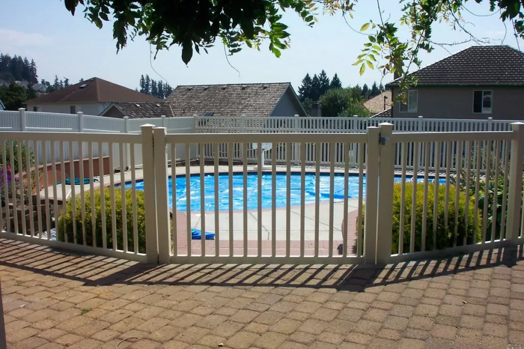 Short, vinyl picket fence protecting a pool to help illustrate choosing the Best fence.